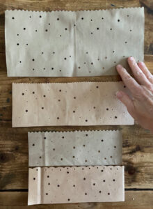 Brown paper bags with decorative cut edge and holes punched to make luminaries