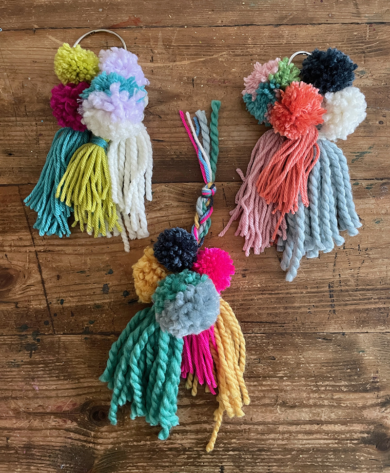 3 finished pom-pom tassel hangers on a table in different color schemes