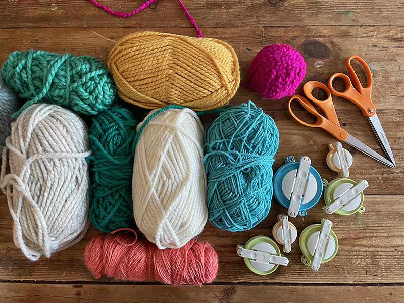 a table with yarn and pom-pom makers
