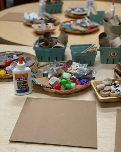 Setting up cardboard and recycled materials on a table for preschoolers to make collages