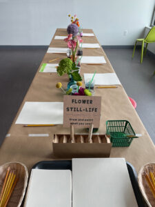 Flower set up with vases of flowers, inviting multi-age children in to observe, draw, and paint.