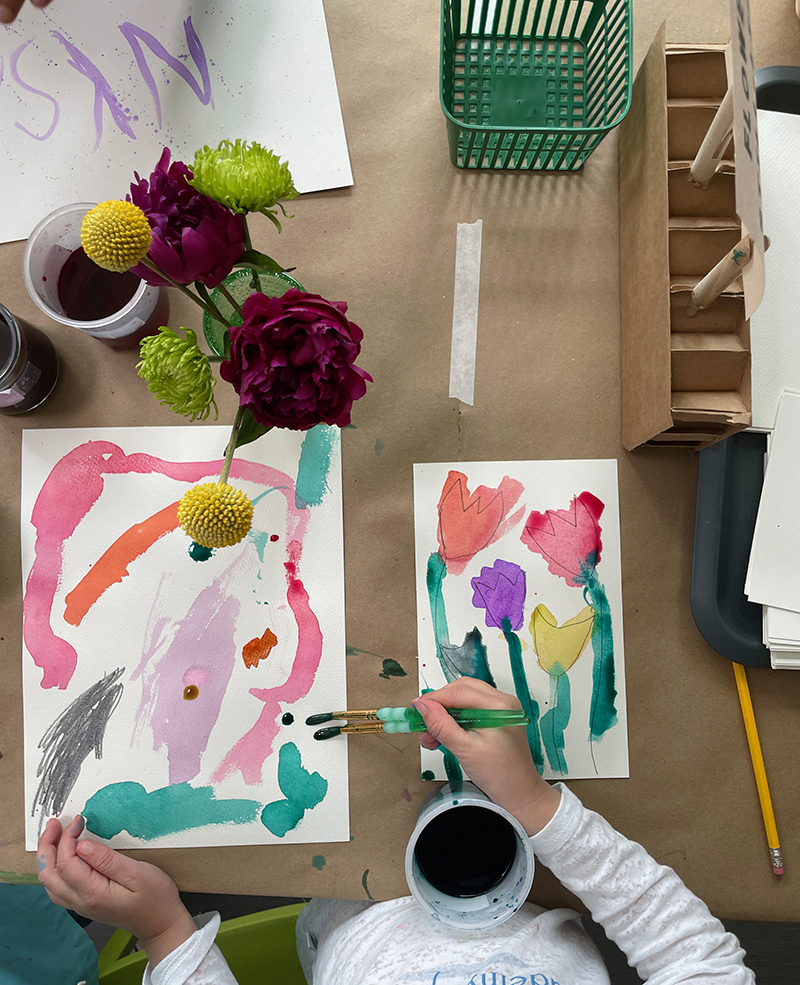 Young child explores liquid watercolor at the flower still-life table.