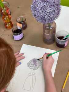 Child draws and paints a flower in a vase.