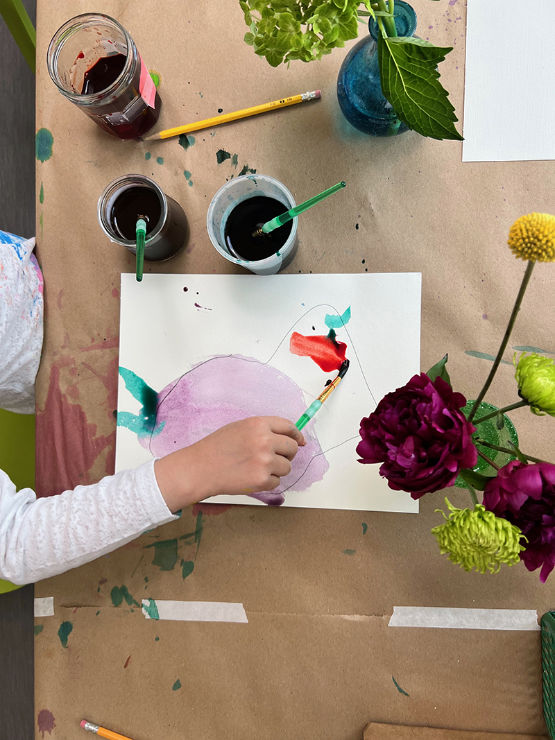 Young child explores drawing and painting a flower-still life using liquid watercolor.
