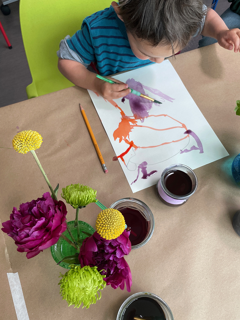 Toddler explores liquid watercolor for the first time, inspired by still-life flower table.