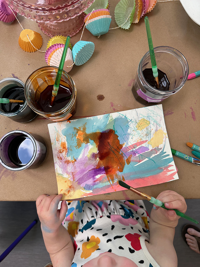 Young child painting with liquid watercolors, inspired by cakes.