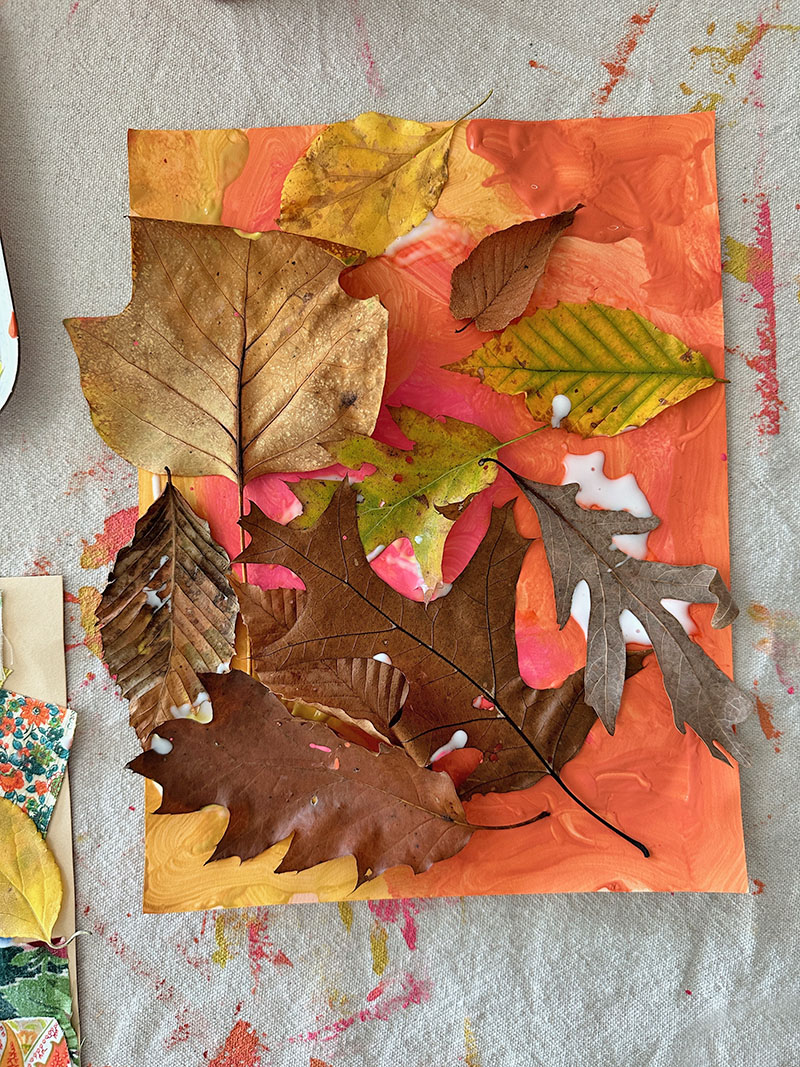 Finished mixed-media artwork using tempera paints, leaves, and fabric scraps.