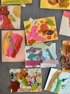 Finished mixed-media artwork created by young children using tempera paints, leaves, and fabric scraps.