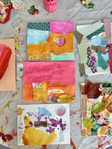 Finished mixed-media artwork created by young children using tempera paints, leaves, and fabric scraps.