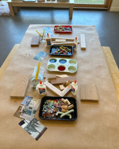A table set up for open-ended exploration with wood, liquid watercolor, collage, and glue.