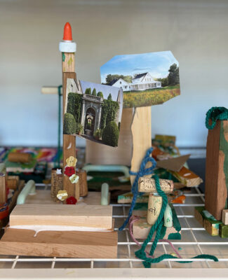Children make sculptures with wood, glue, magazines, and other collage materials and dry them on a rack.