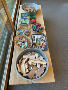 A table set up for open-ended exploration with wood, liquid watercolor, collage, and glue.