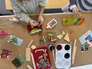 Children build and create with wood, liquid watercolor, collage, and glue.
