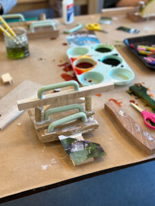 Children build and create with wood, liquid watercolor, collage, and glue.