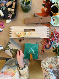Child cutting magazine clippings to add to her painted wood collage.