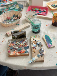 Mixed-media wood structure made by a young child using puzzle pieces, sand paper, and magazine clippings.