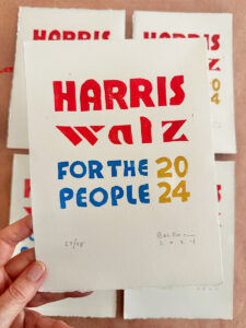 Hand holding one handmade Harris Walz collagraph print in primary colors.