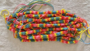 A pile of finished rainbow tube knittings ready to make bracelets.
