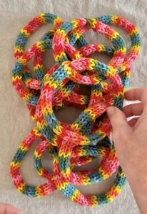 A pile of rainbow tube knitted bracelets.