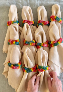 A display of napkins on a table using rainbow tube knitted napkin holders.
