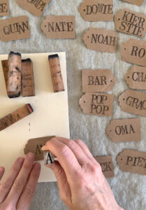 Using alphabet stamps to make placecards with brown paper bags.