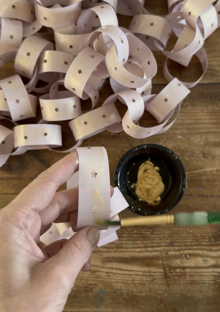Make a paper chain using any paper that you have, a star hole punch, and some gold paint for a festive, shimmering room decor.
