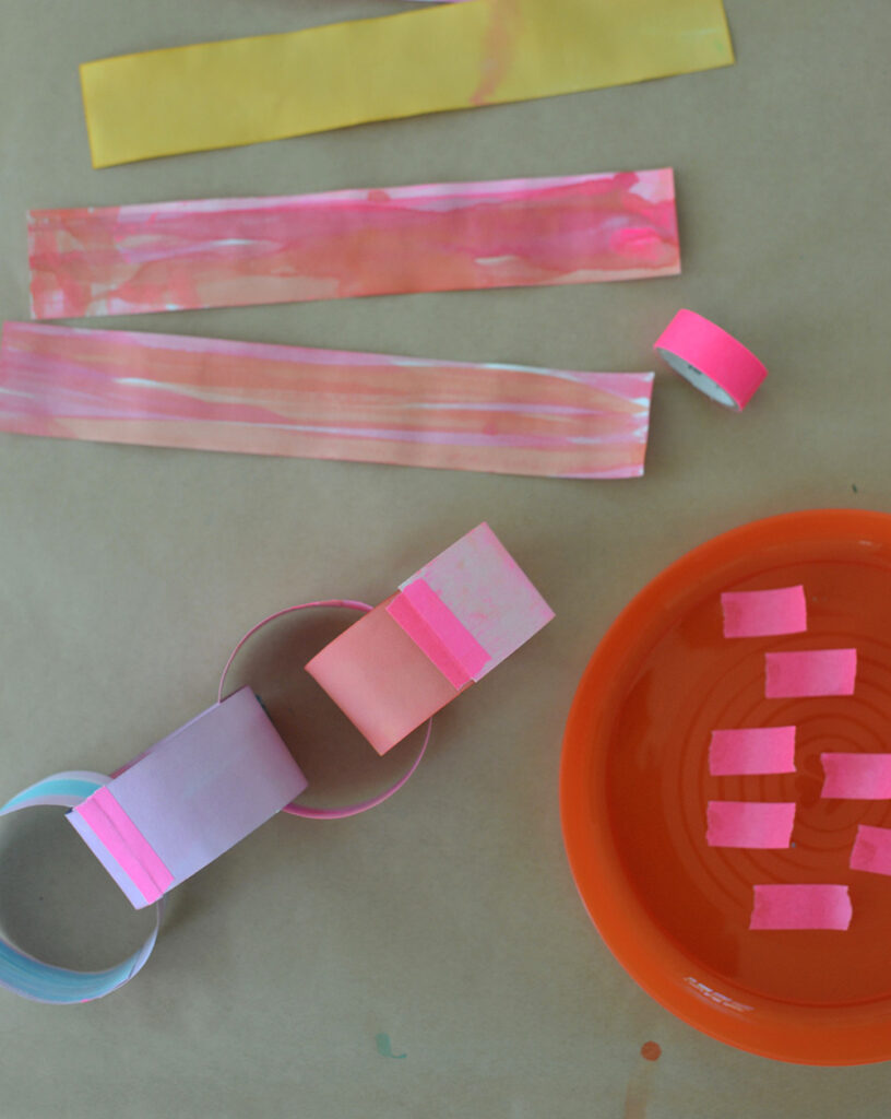 Make a colorful, rainbow paper chain using hand painted paper and neon tape.